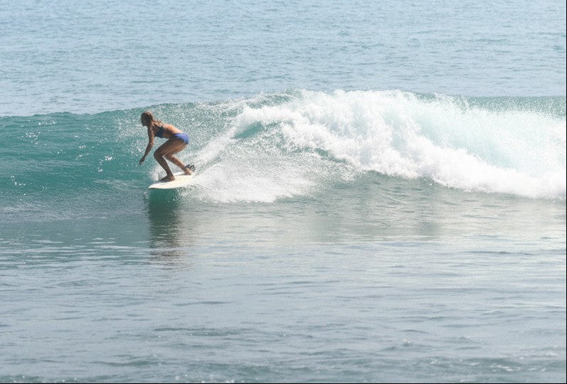 Flipflop and Treacle scalloped black recycled nylon bikini top and bottoms on surfer riding a wave